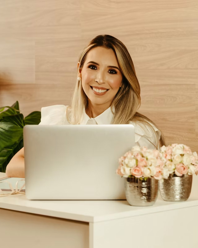 Profissional de estética sorrindo enquanto usa o notebook
